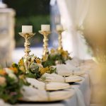 Luxurious outdoor wedding table setting with flowers and candlesticks.