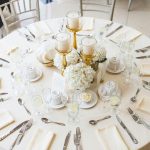 Beautifully arranged dining table setting with candles and floral centerpiece, perfect for a wedding reception.