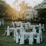 Charming sunset-lit outdoor wedding setup with adorned tables and chairs, perfect for celebrating love.